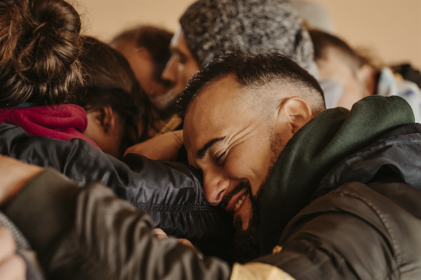 Une étreinte de groupe entre hommes, un visage au centre, yeux fermés